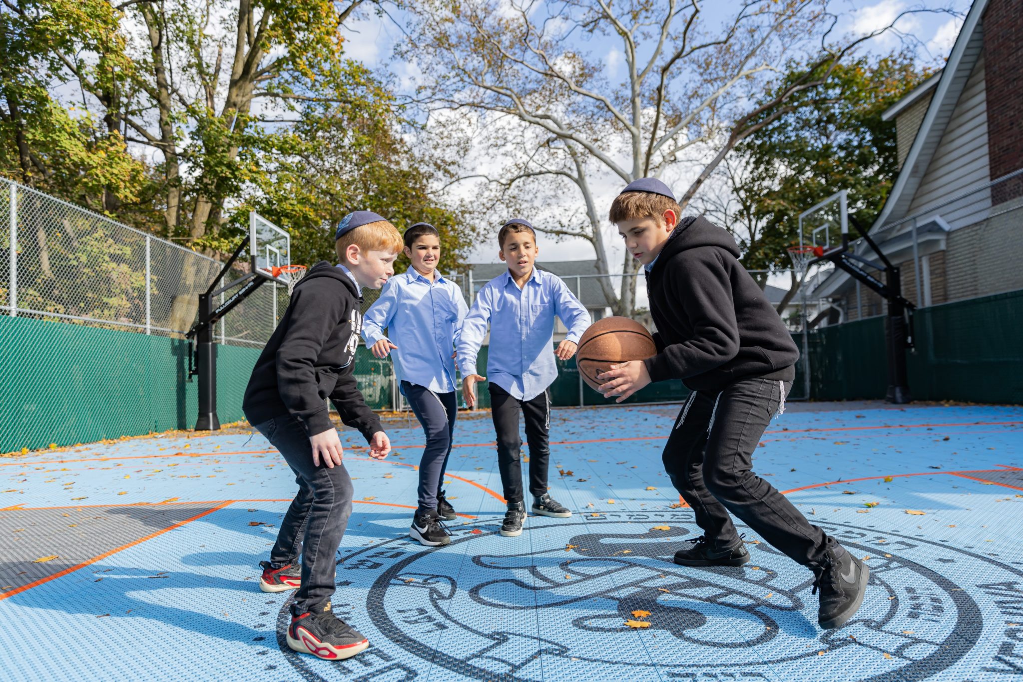 Talmidim playing basketball on the backyard court, rebuilt in 2023.